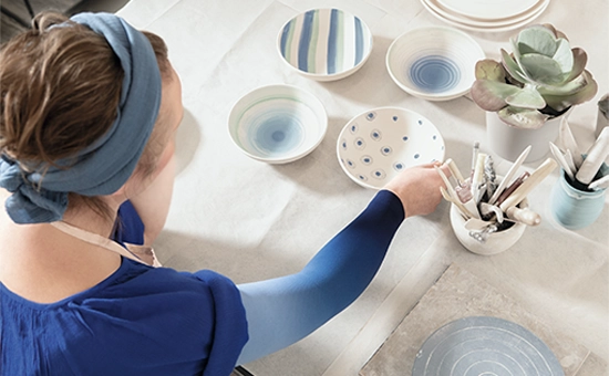 Frau trägt blauen Kompressionsarmstrumpf bei kreativer Tätigkeit<br />
